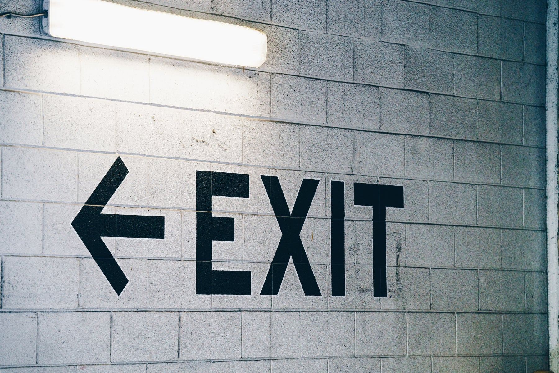 An exit sign with an arrow painted on a block wall